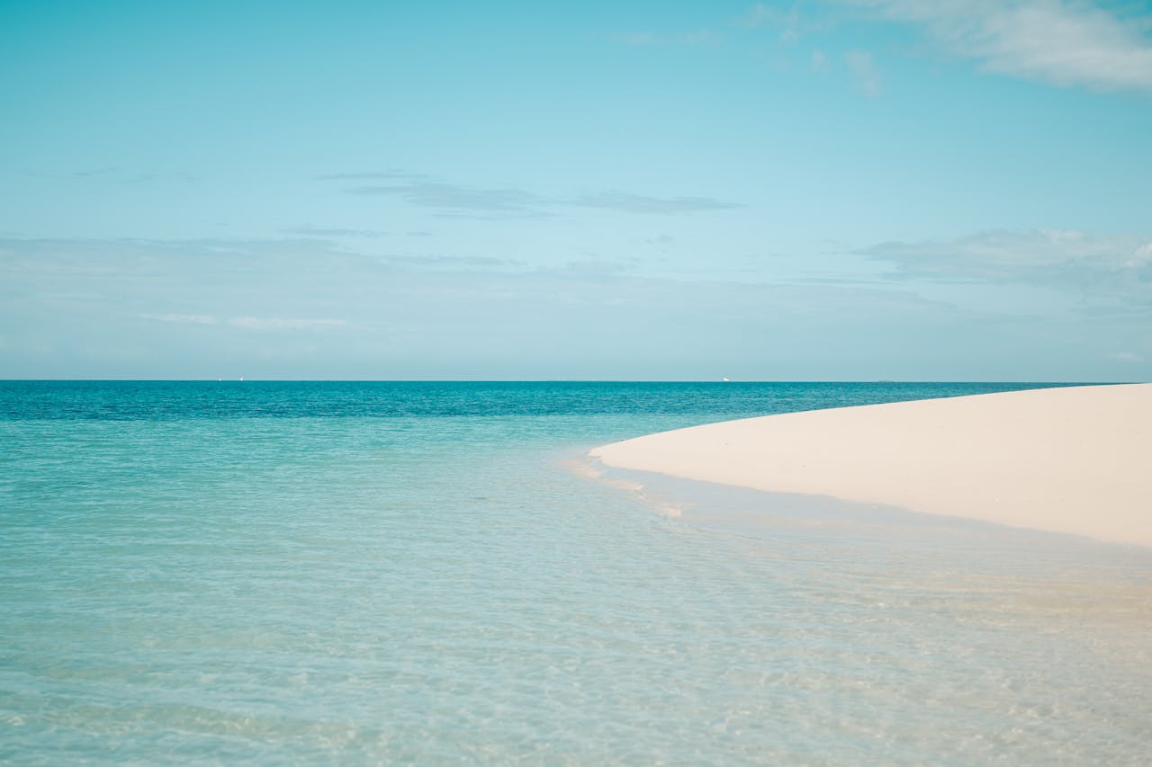 Pristine white sandy beach with clear turquoise ocean in Zanzibar, Tanzania, under a bright summer sky.