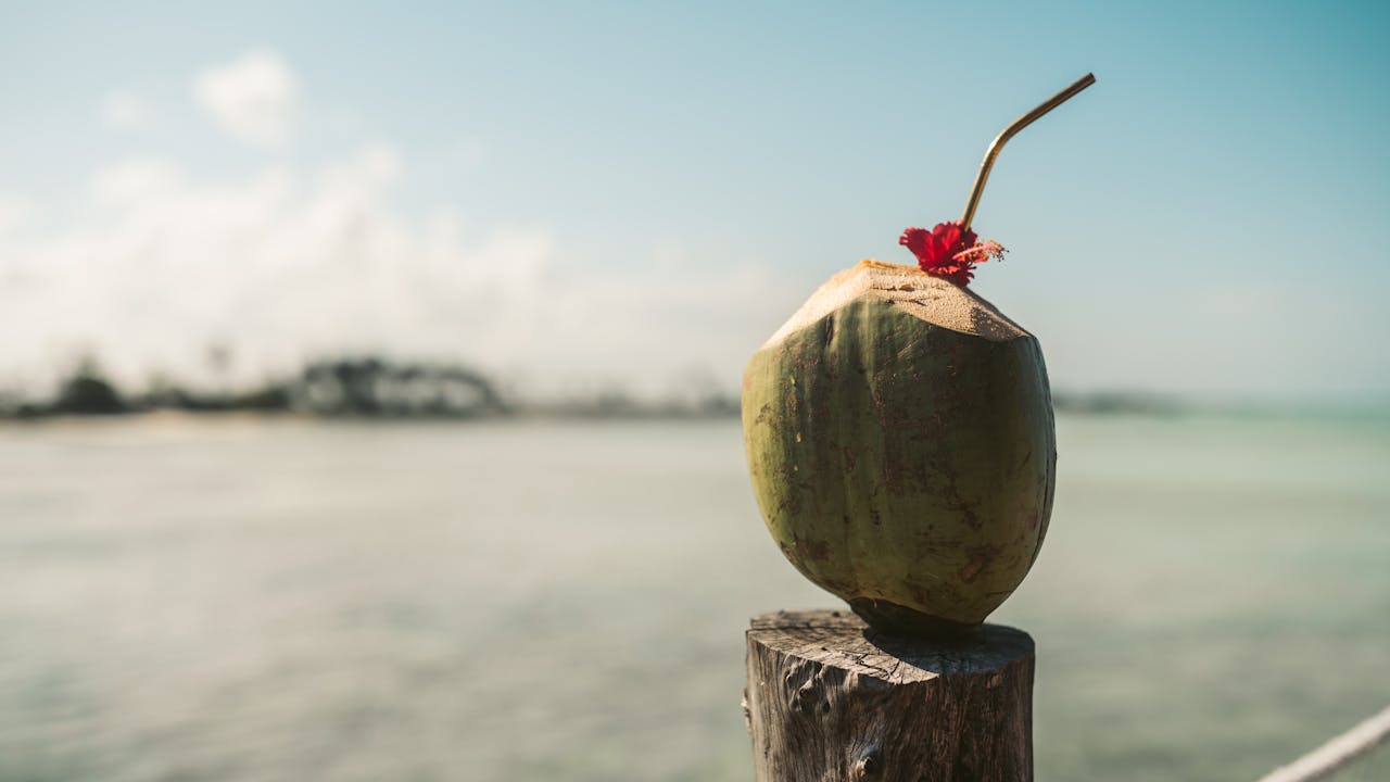 Enjoy a fresh coconut drink with a floral garnish on a sunny beach in Zanzibar.