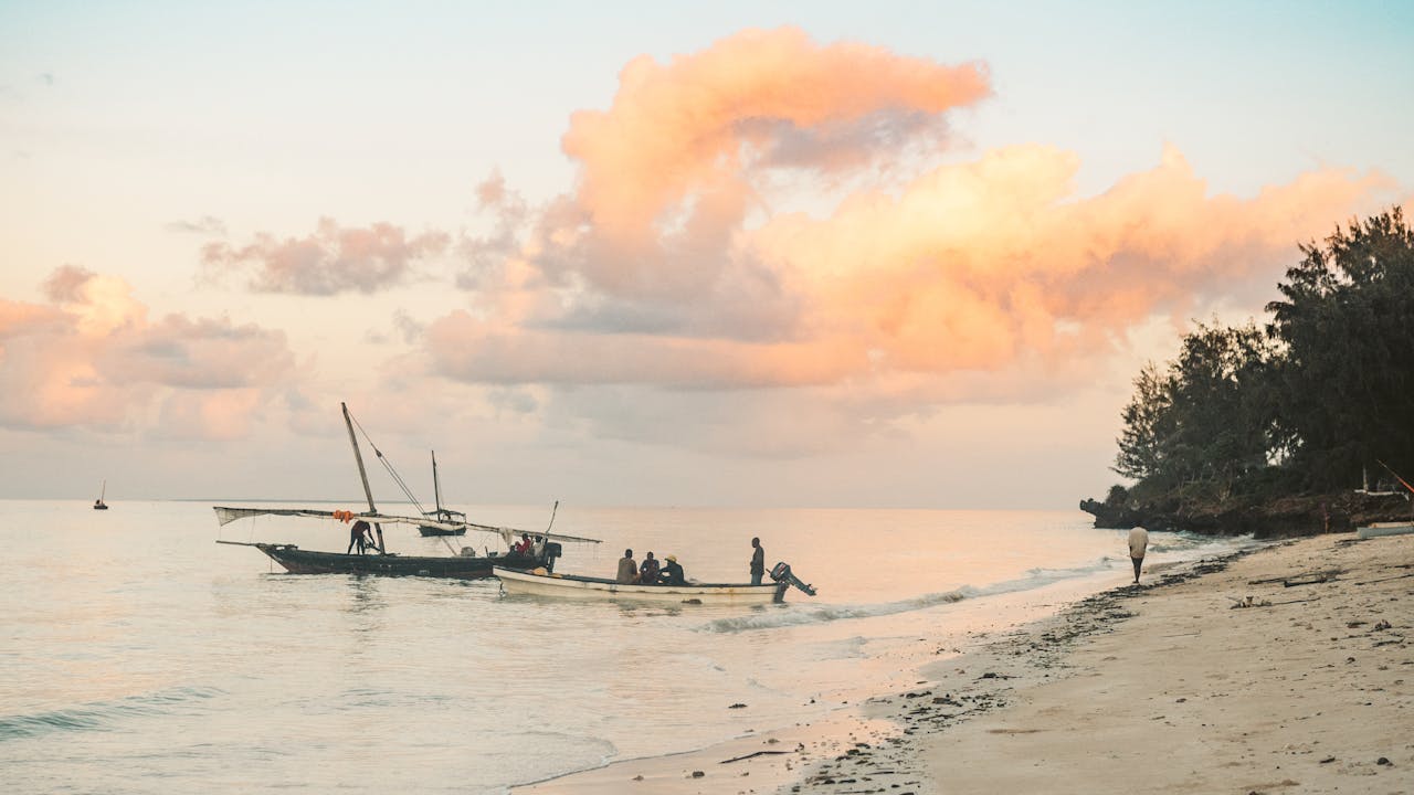 Fishermen returning to shore at sunrise on Zanzibar's tranquil coastline.